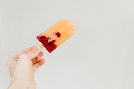 Fruit homemade popsicle made is from fresh mango  blackcurrant and coconut milk  Minimal photography style