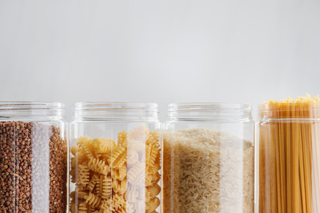 Various pasta and cereal grains in plastic jars for a long storage