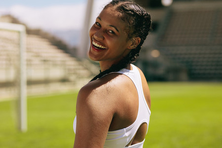 Sportswoman smiling at sports field