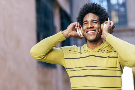 Black man listening to music with wireless headphones sightseeing in Granada