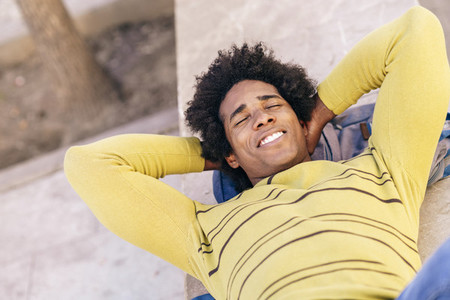 Black tourist with afro hair lying on the ground outdoors
