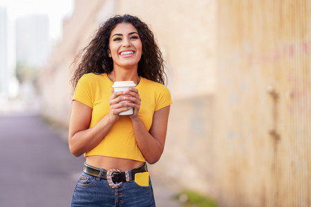 Arab girl walking across the street with a take away coffee