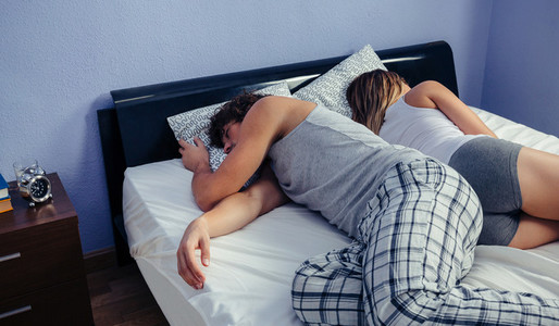 Couple sleeping on their backs uncovered