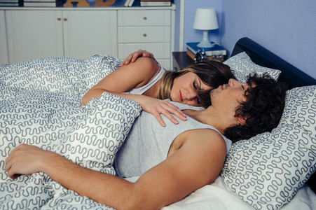 Couple sleeping embraced in bed