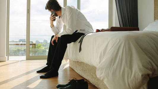 Businessman making phone call while getting ready for office