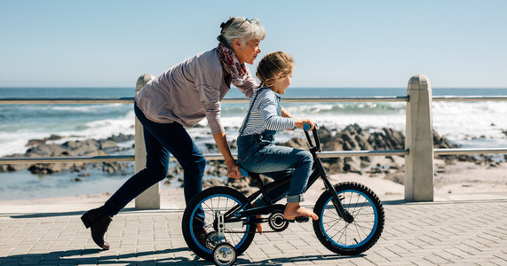 Senior woman teaching a small girl to ride a bicycle