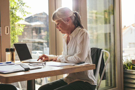 Senior businesswoman working on laptop at coffee shop