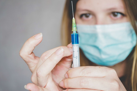 Young woman wearing a face mask and hold a vaccine