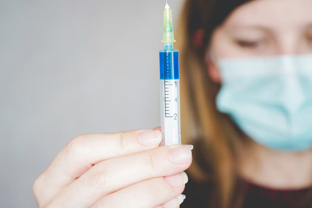 Young woman wearing a face mask and hold a vaccine
