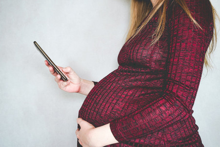 Young pregnant woman searching information with her smartphone