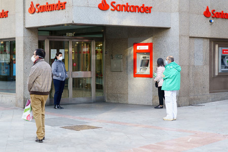 GRANADA  SPAIN  23RD APRIL  2020 People waiting in line at the bank protected by masks
