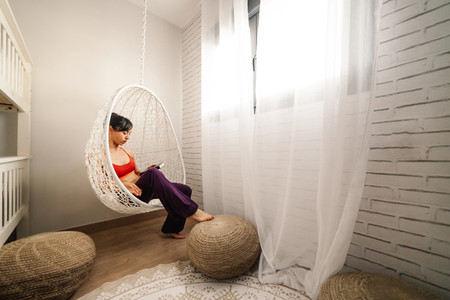 Woman reading a book in a hammock in her bedroom