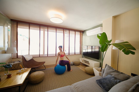 woman practicing yoga in her apartment in front of the window