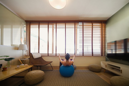 woman practicing yoga in her apartment in front of the window