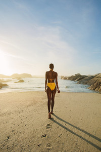 Woman in bikini walking towards the sea