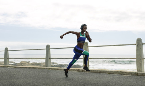 Athletic woman running on seaside promenade