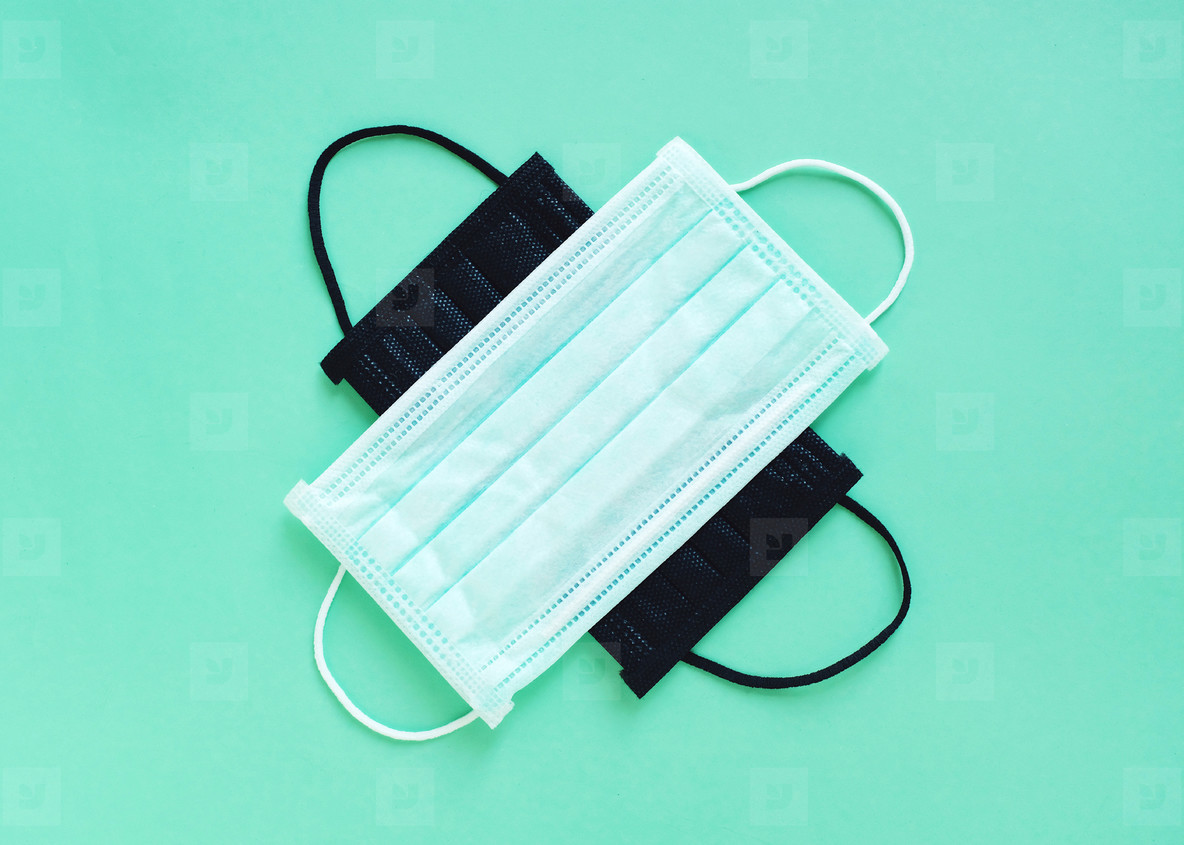 Flat lay of hygienic masks on bright pastel green color backgrou