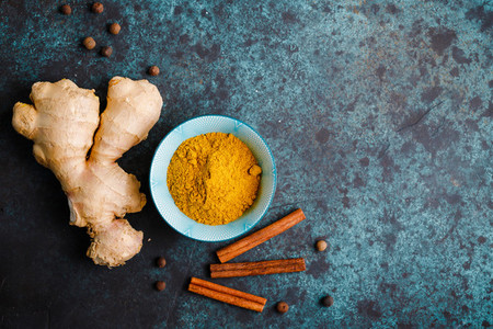 Ingredients for preparation turmeric latte  Curcuma  ginger  cinnamon and allspice on a blue background