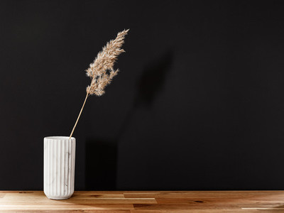 Reed in a white marble vase on a wooden table against black wall  Interior minimal background  copy space