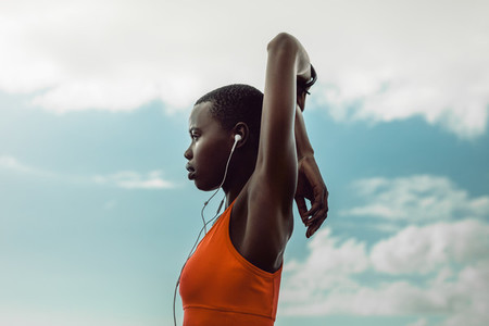 African woman with earphones doing stretching exercise