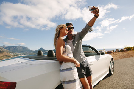 Beautiful couple taking pictures of themselves on road trip
