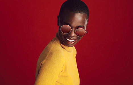Fashionable woman in sunglasses on red background