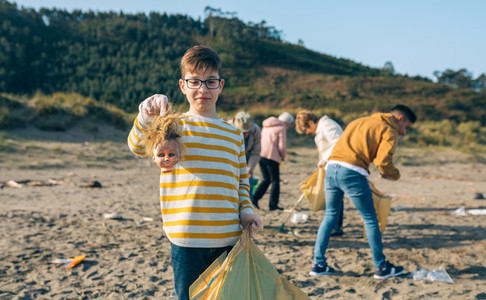 Boy showing doll head while cleaning the beach