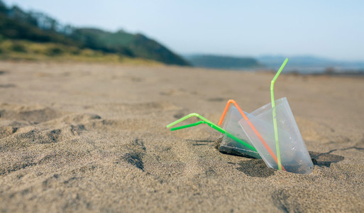 Beach with plastic cups and straws