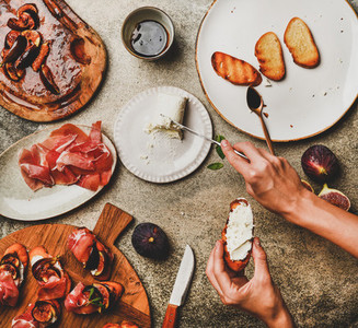 Crostini with prosciutto  figs and womans hands spreading cheese