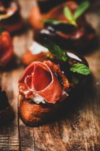 Crostini with prosciutto  goat cheese and figs on wooden board