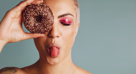 Woman holding a donut and sticking out tongue
