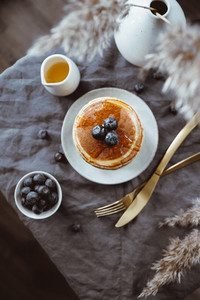 Top view of American traditional pancakes with honey and fresh blueberry