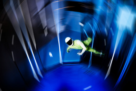 A man flier doing stunts in an indoor wind tunnel