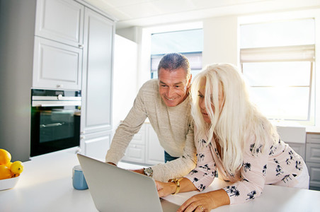 Fun senior couple looking at computer in kitchen