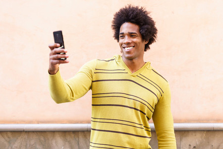 Black man with afro hair and headphones using smartphone