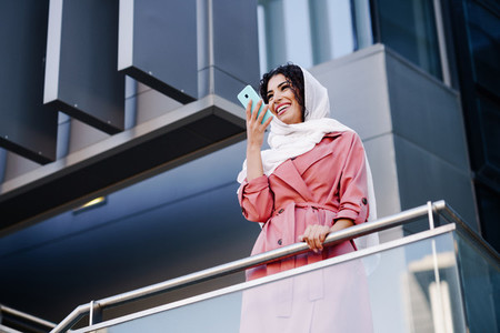 Muslim Woman with hijab recording voice note with a smartphone