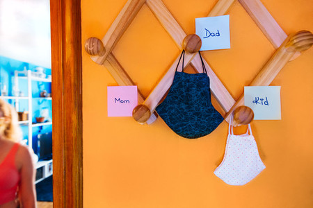 Surgical masks of family hanging on the coat rack with labels