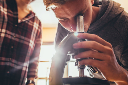 High school student using a microscope in a science class