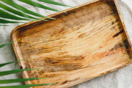 Wooden tray is made from mango tree on a linen cloth decorated palm leaf  Eco friendly and summer mock up