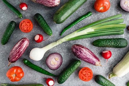 Colorful summer pattern with different fresh vegetables on a grey background Flat lay top view