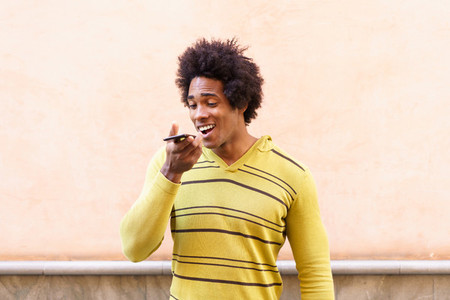 Black man with afro hair and headphones using smartphone