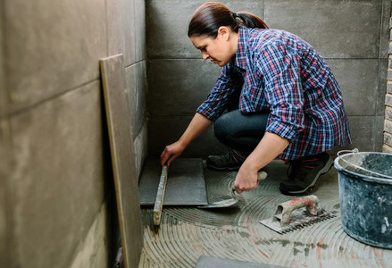 Female bricklayer checking floor with a level