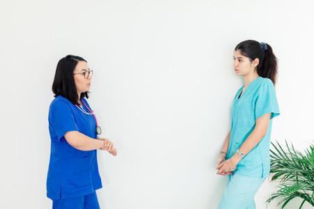 Female doctor and nurse talking with withe background wall