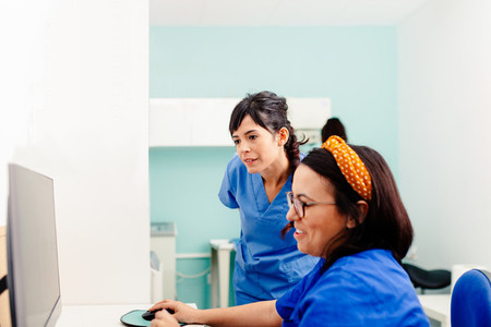 Two nurses using a computer in a x ray room
