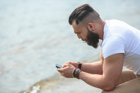 American Bearded Man using phone near the river