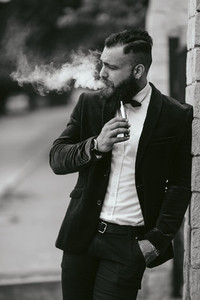 A rich man with a beard smokes electronic cigarette