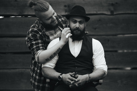 barber shaves a bearded man in vintage atmosphere