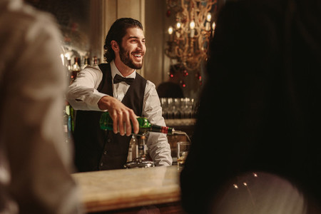 Bartender serving drink to guest at bar