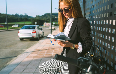 Businesswoman reading diary with her scooter next