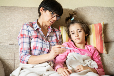 Mother measuring her daughters temperature to check for fever